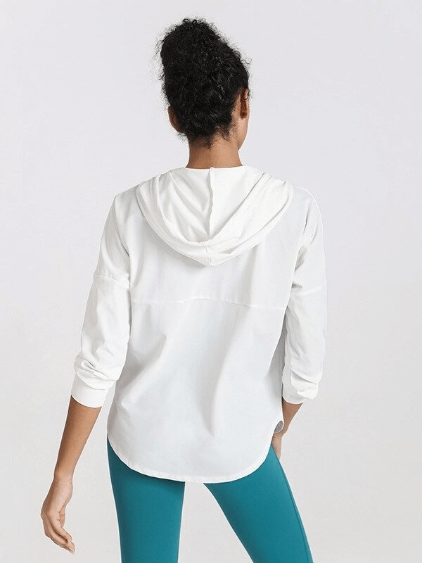 Woman wearing a white loose sports jacket with hood, perfect for training, shown from the back.